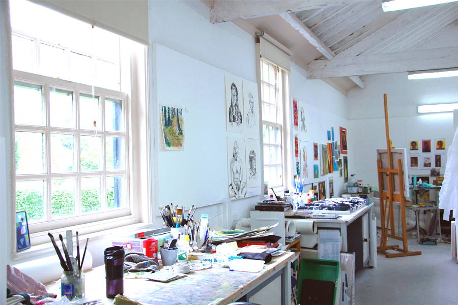 A college art room with easels in the background, lots of colour palettes and paints.